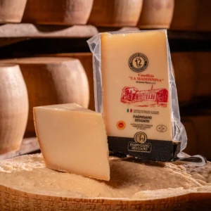 Punta di Parmigiano Reggiano 12 mesi fresca posizionata sopra una forma intera.