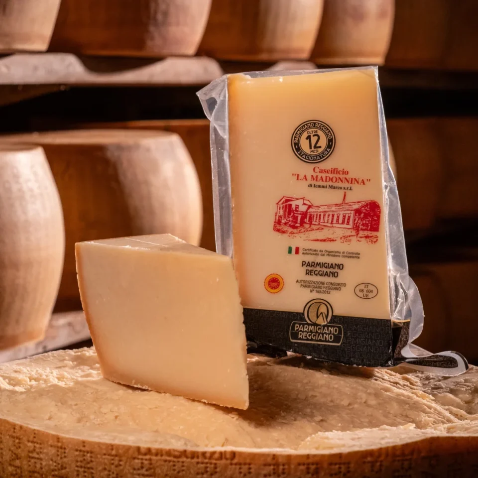 Punta di Parmigiano Reggiano 12 mesi fresca posizionata sopra una forma intera.