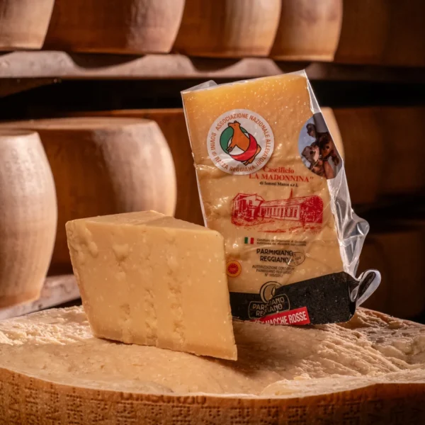 Parmigiano Reggiano Vacche Rosse poggiato sulla maestosa forma di produzione.
